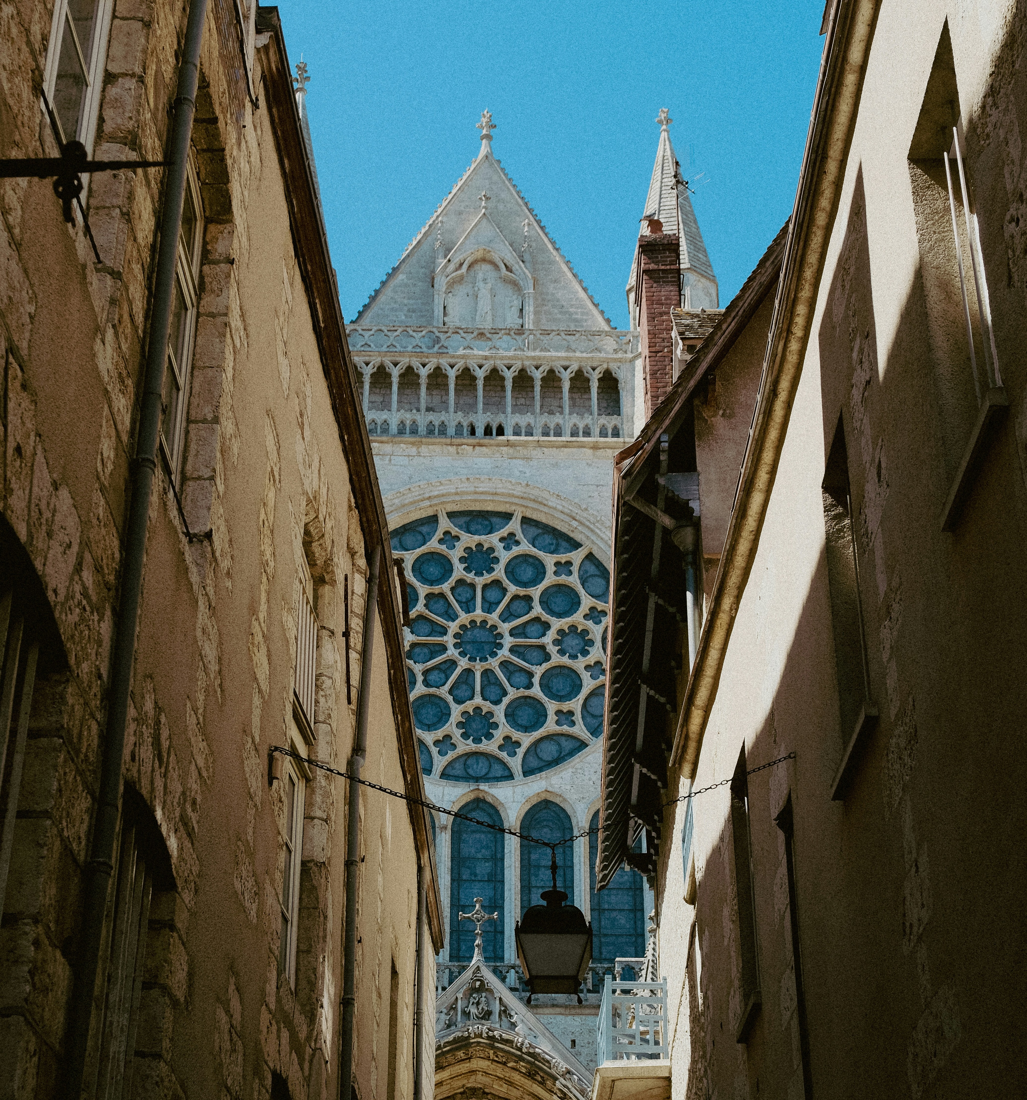 A photograph looking up at Chartres Cathedral from between two buildings.