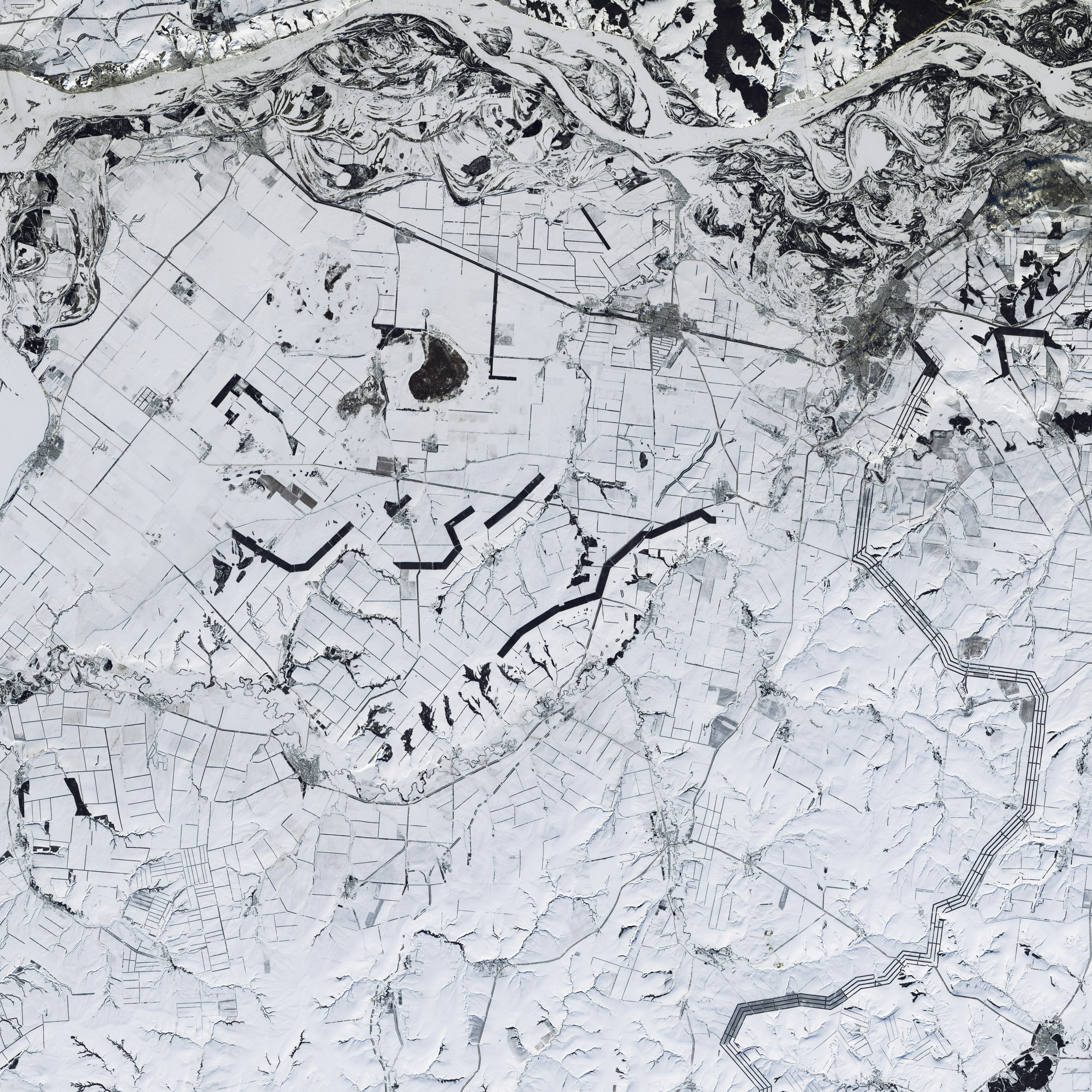 A black and white aerial photograph with roads and rivers in distinct view on snow-covered ground.