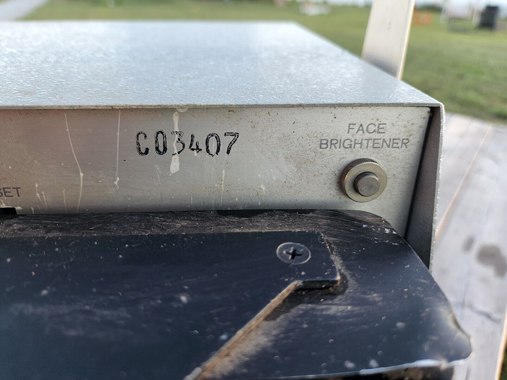 An up-close photograph of the button labelled “Face brightener” on the back of the Polaroid ID-2.
